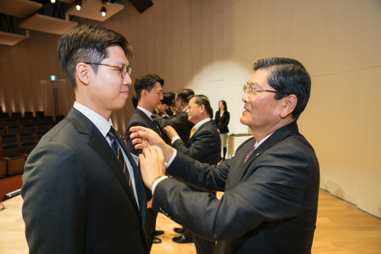 차남규 한화생명 부회장이 2019년 신입사원들에게 사령장 수여와 함께 회사 배지를 달아주고 있다. 한화생명 제공